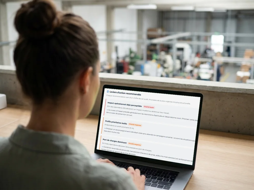 Une responsable RH à son bureau, vue de dos, consulte sur son ordinateur les leviers d'action recommandés par la restitution : impact opérationnel déjà perceptible, profils prioritaires isolés, port de charges dominant.